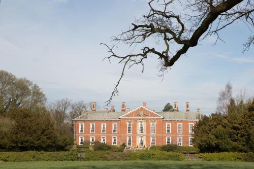 un gran edificio de ladrillo rojo con un árbol delante de él en Bosworth Hall Hotel & Spa, en Market Bosworth