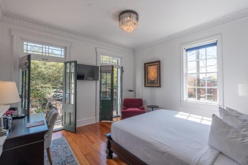 a bedroom with a bed and a desk and windows at Royal Frenchmen Hotel and Bar in New Orleans