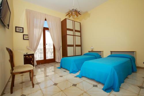 1 dormitorio con 2 camas con sábanas azules y silla en Sine Tempore, en Sorrento