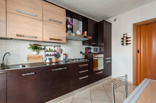 a kitchen with dark wood cabinets and a sink at Hostly - Family Home Strada dell'Olio - Brand new 2BR, 2 Bathrooms with AC in Cascina