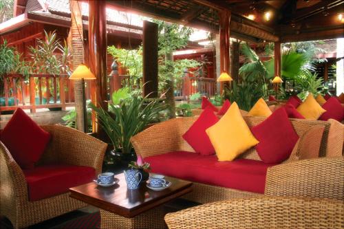 a couch with red and yellow pillows on a patio at Angkor Village Hotel - Small Luxury Hotels of the World in Siem Reap