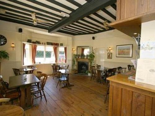 a dining room with tables and chairs and a fireplace at Bolingbroke Arms & Hotel in Swindon