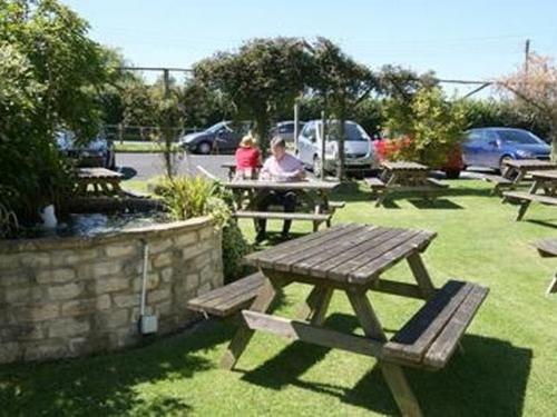 dos personas sentadas en una mesa de picnic en un parque en Bolingbroke Arms & Hotel en Swindon