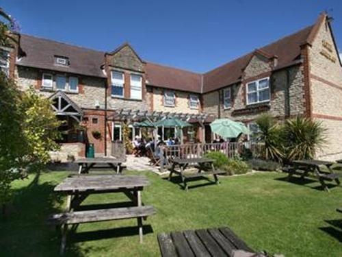 a building with picnic tables in the yard at Bolingbroke Arms & Hotel in Swindon