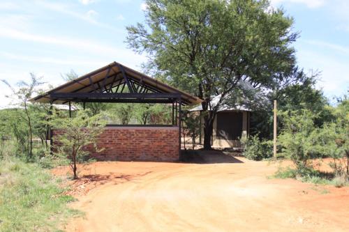 a brick building with a roof on a dirt road at Casa Cara Resort in Parys