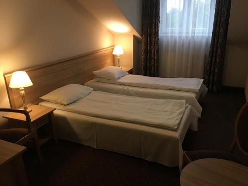 a hotel room with two beds and a table at Hotel&Restauracja Złote Runo in Góra Kalwaria
