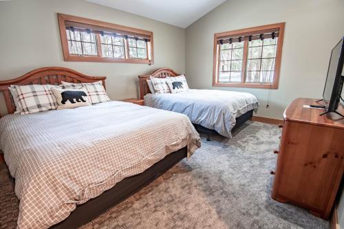 a bedroom with two beds and a tv and two windows at 652 Disciples Village in Boyne Falls
