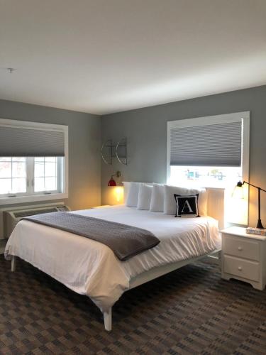 a bedroom with a large white bed with two windows at Acadia Hotel - Downtown in Bar Harbor
