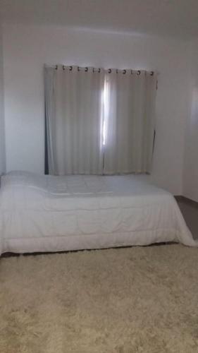 a white bed with a curtain in a bedroom at casa de praia com piscina e hidromassagem in Arraial do Cabo