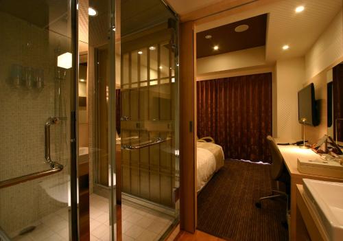 ein Bad mit Dusche und ein Bett in einem Zimmer in der Unterkunft Hotel Coco Grand in Takasaki
