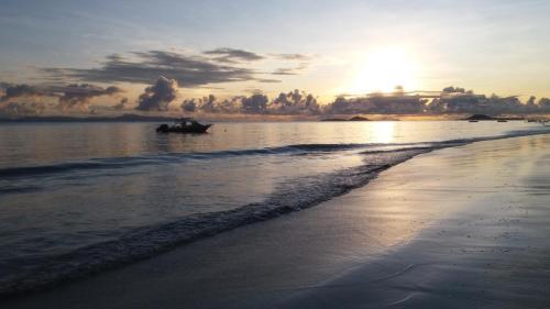 a boat in the water on the beach at sunset at Destination Self-Catering in Grand'Anse Praslin