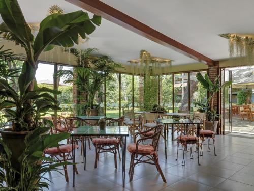 a restaurant with tables and chairs and plants at Hotel Hermitage in Forte dei Marmi