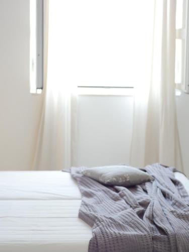 a white bed with a pillow and a window at Galini Rooms & Apartments in Finikas