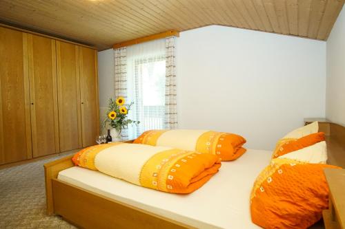 1 Schlafzimmer mit 2 Betten mit orangefarbenen und gelben Kissen in der Unterkunft Home in the Alps in Ratschings