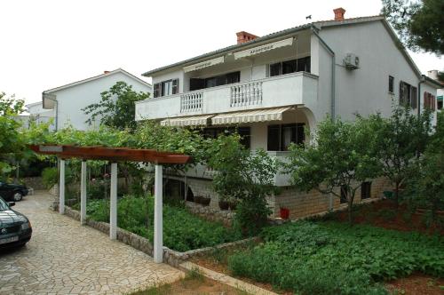 a white building with a balcony on a street at Apartments Jurina in Krk