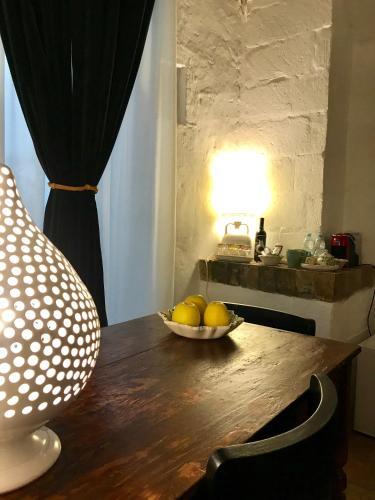 a bowl of fruit on a wooden table with a lamp at Ponticelli B&B Boutique in Gravina in Puglia