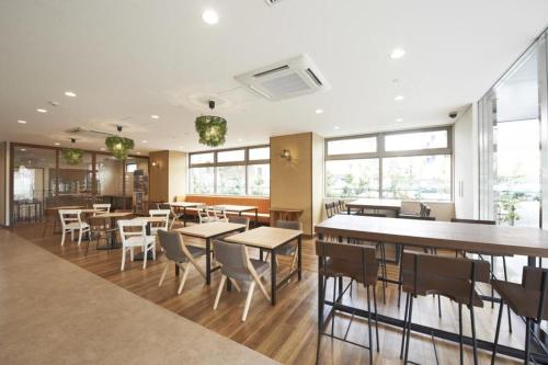 a dining room with tables and chairs and windows at Hotel Sun Clover Koshigaya Station - Vacation STAY 55366 in Koshigaya