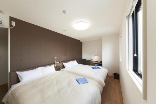 越谷市にあるHotel Sun Clover Koshigaya Station - Vacation STAY 55377のベッドが2つと大きな窓がある寝室