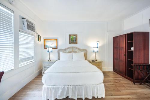 una camera bianca con un letto e due lampade di Four Flowers Guesthouse a Key West
