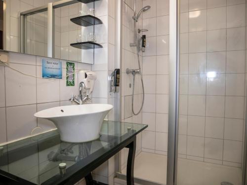 La salle de bains est pourvue d'un lavabo et d'une douche. dans l'établissement Hotel Hague Center, à La Haye