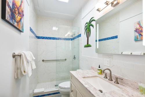 bagno con lavandino, servizi igienici e specchio di Four Flowers Guesthouse a Key West