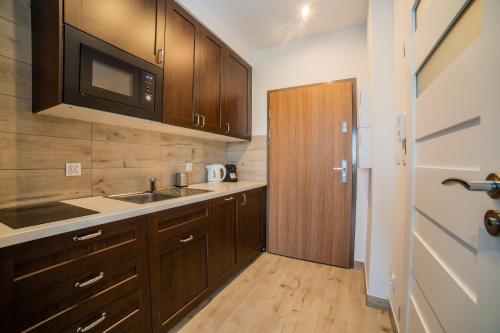 a kitchen with wooden cabinets and a sink and a microwave at Apart Harmony - Apartamenty Nexo in Puck