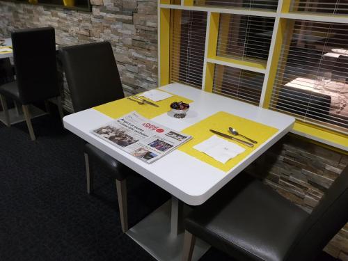 ein weißer Tisch mit schwarzen Stühlen und einer Zeitung darauf in der Unterkunft Logis Hôtel A la Bonne Auberge in Laval