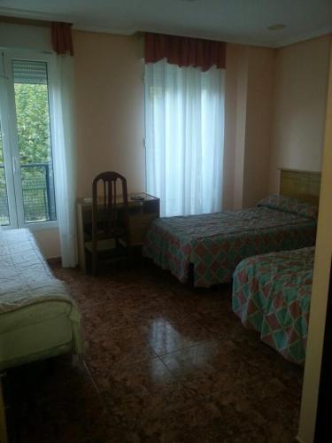 a hotel room with two beds and a chair at Hotel Durtzi in Sobrón