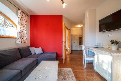 a living room with a couch and a red wall at Butorowy Dwór in Kościelisko