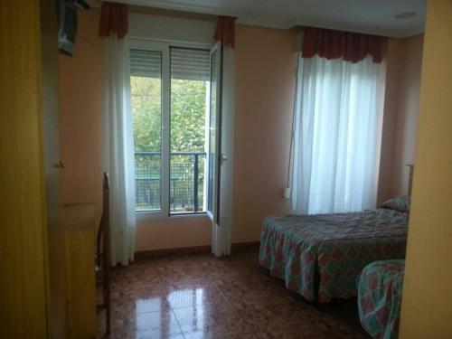 a bedroom with a bed and a large window at Hotel Durtzi in Sobrón