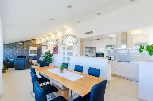 a kitchen and dining room with a wooden table and blue chairs at Villa Art Gallery in Mlini