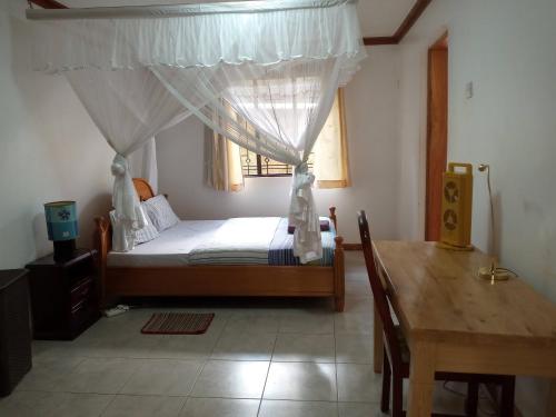 een slaapkamer met een bed, een tafel en een raam bij Hospitality Connect in Kampala