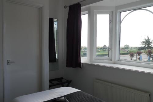 a bedroom with two windows and a bed in it at Gable End Hotel in Great Yarmouth