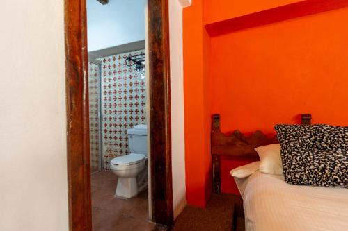 a bathroom with a toilet and an orange wall at Hosteria del Frayle in Guanajuato