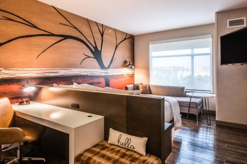 a hotel room with a bed with a tree mural on the wall at Cambria Hotel McAllen Convention Center in McAllen