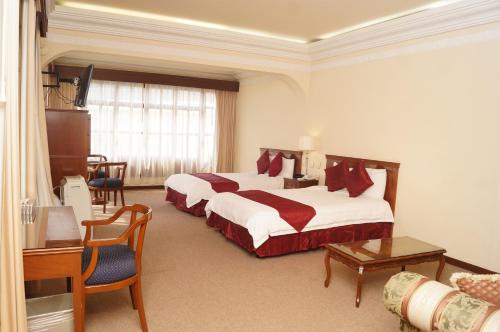 Cette chambre comprend deux lits et une télévision. dans l'établissement Hotel Hacienda de los Ángeles by Rotamundos, à Comitán de Domínguez