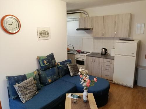 a living room with a blue couch and a kitchen at APARTMAN NENA in Karlovac