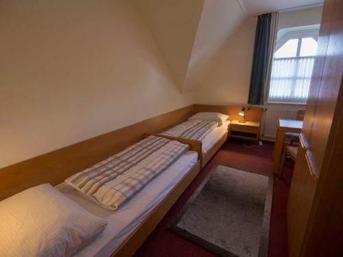 2 łóżka w małym pokoju z oknem w obiekcie 176 Ferienwohnungen Schmidt_s Auss w mieście Horumersiel