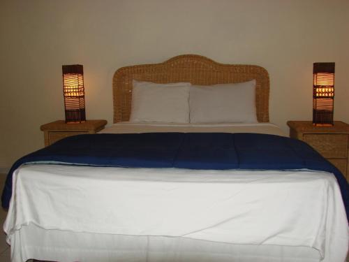 a bedroom with a bed with two lamps on tables at Cunucu Villas - Aruba Tropical Garden Apartments in Oranjestad