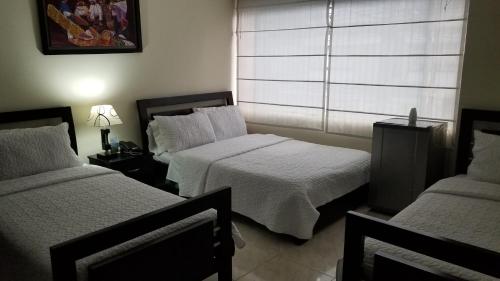 a hotel room with two beds and a window at Hotel Sweet Home in Bogotá