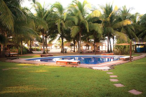 a swimming pool in a yard with palm trees at Bambuddha Centro Holistico in Barra Vieja