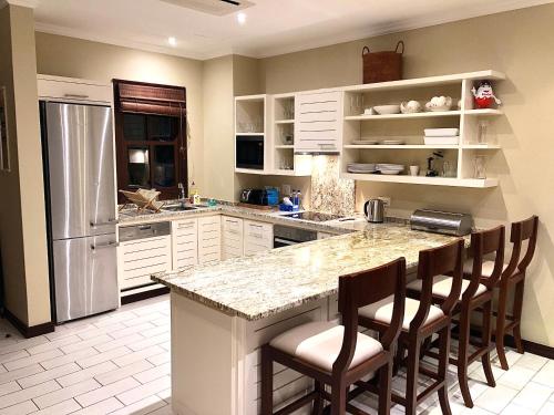 a kitchen with a counter with chairs and a refrigerator at Eden Island Apartment - P14A3 in Eden Island