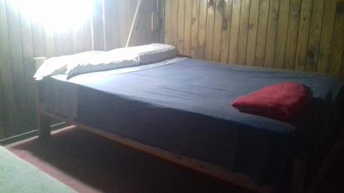 a bed with a blue blanket and a red pillow on it at Bungalows Maneyros in Gualeguaychú