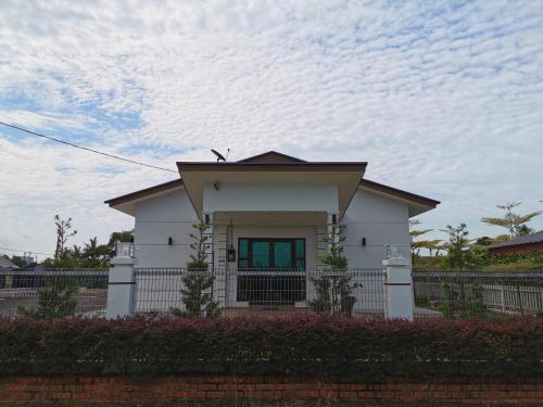 ein weißes Haus mit einem Zaun davor in der Unterkunft Orchard Villa Melaka in Malakka