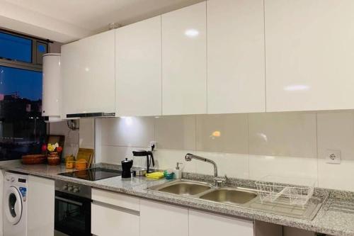 a kitchen with white cabinets and a sink at Braga Forum House in Braga