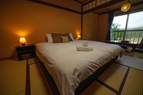 a bedroom with a large white bed with a window at HA-MON Slope Side Hotel and Private Chalet in Otari