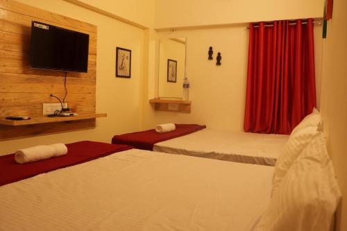 a hotel room with two beds and a flat screen tv at Grand Suites Srirangam in Tiruchchirāppalli