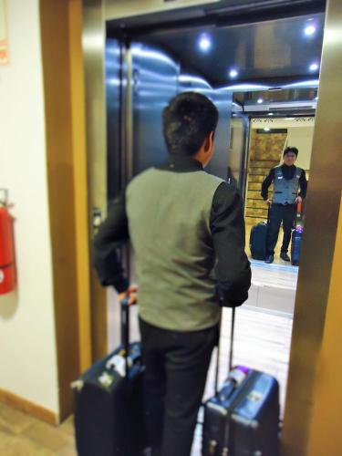 a person with luggage looking at a man in a mirror at San Francisco Cusco Hotel in Cusco