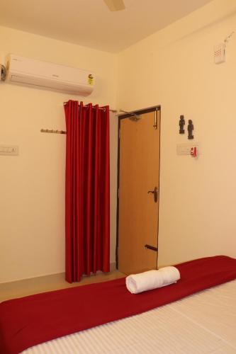 a bedroom with a red curtain and a door at Grand Suites Srirangam in Tiruchchirāppalli