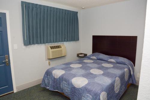 a bedroom with a bed and a window with a fan at Comet Motel in Los Angeles